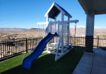 White and blue vinyl playset featuring an elevated tower, slide, and front climbing access.