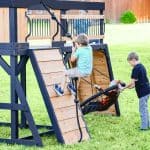 Children enjoying outdoor playset with slide and swing in backyard.