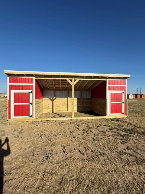 Red and white loafing shed with open front on a Texas farm.