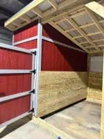 Red and natural wood loafing shed for livestock in Texas.