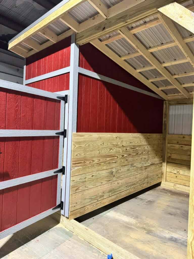 Red and natural wood loafing shed for livestock in Texas.