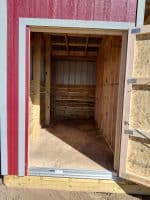 Wooden loafing shed with open door, perfect for outdoor play and relaxation.