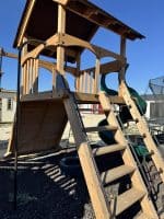 Wooden outdoor playset with slide and climbing stairs for kids in Texas.