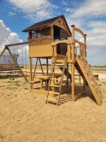Colorful wooden playground with slide and swings for children in Texas outdoor park.