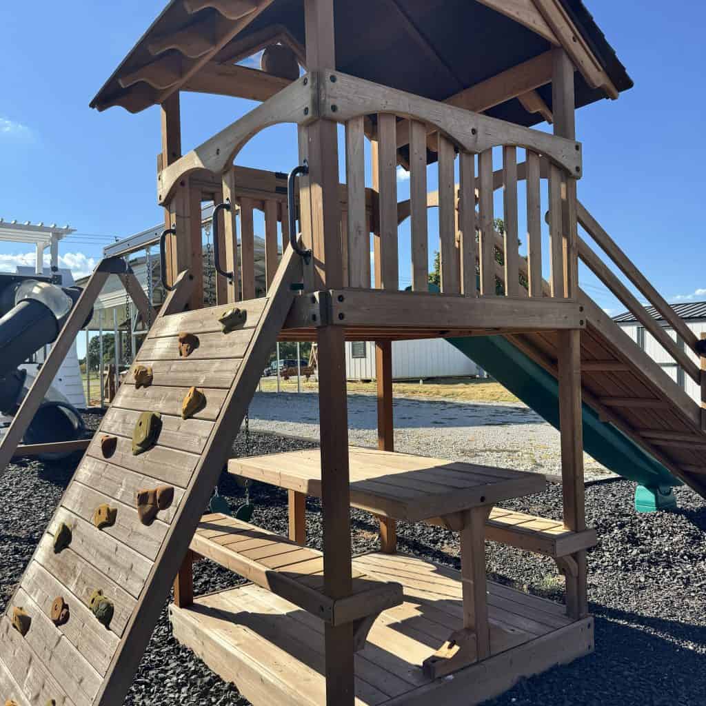Durable wooden playground with slide and climbing wall for children.