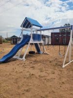 Outdoor playground with slide and swings in Texas backyard.