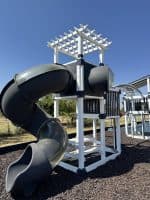 Children's outdoor playground slide with a tunnel and climbing frame.