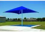 Blue square fabric shade over a concrete pad in a park setting.