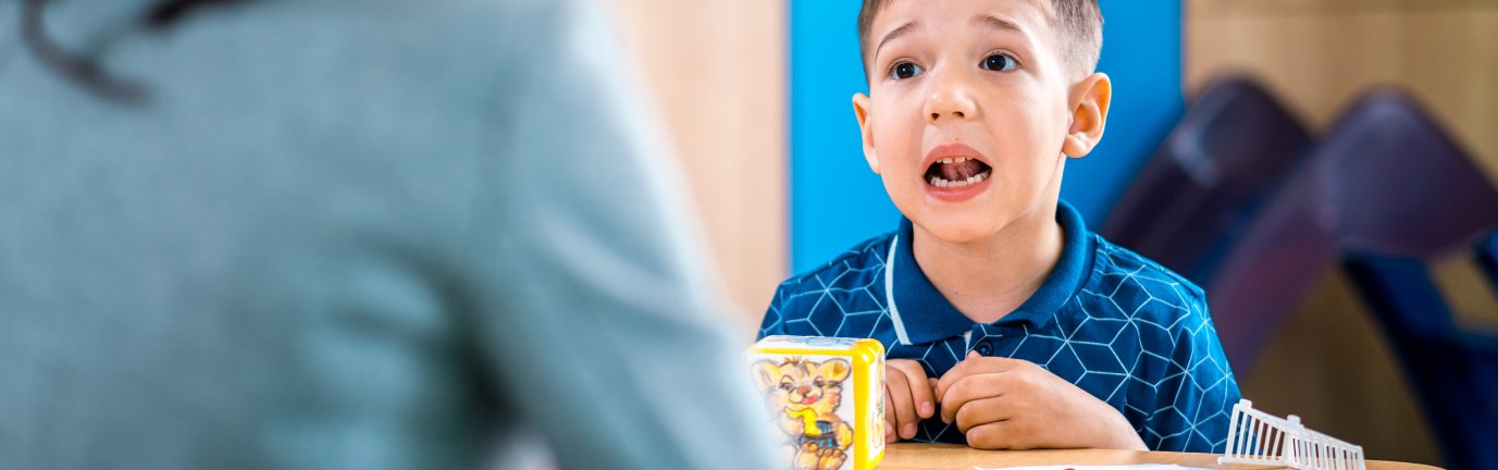 Bambino che fa esercizi di logopedia con la logopedista