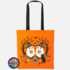 Two ghosts in witch hats holding orange mugs beside a campfire, with a black cat, pumpkins and autumn trees, printed on a tote bag in orange and black - Print Unleashed