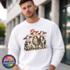 Three wide-eyed Christmas cows tangled in colourful lights, one wearing a Santa hat and another holding a candy cane, printed on a white unisex sweatshirt male model - Print Unleashed