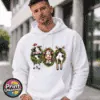 Three Christmas cows in festive wreaths, one wearing a Santa hat and another facing backwards with antlers and striped leg warmers, printed on a white unisex hoodie male model - Print Unleashed