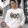 Three Christmas cows in festive wreaths, one wearing a Santa hat and another facing backwards with antlers and striped leg warmers, printed on a white unisex sweatshirt female model - Print Unleashed