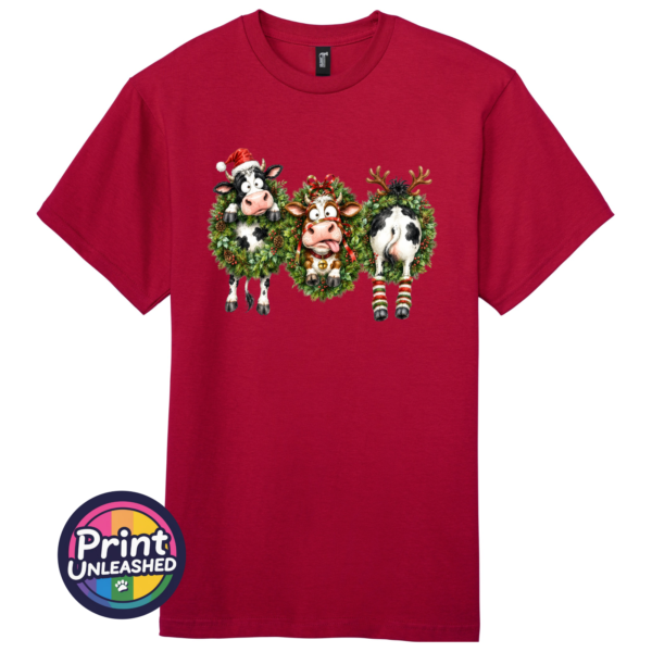 Three Christmas cows in festive wreaths, one wearing a Santa hat and another facing backwards with antlers and striped leg warmers, printed on a cherry red premium unisex T-shirt - Print Unleashed