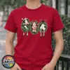 Three Christmas cows in festive wreaths, one wearing a Santa hat and another facing backwards with antlers and striped leg warmers, printed on a cherry red premium unisex T-shirt female model - Print Unleashed