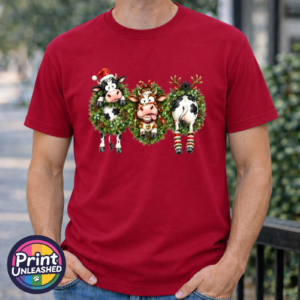 Three Christmas cows in festive wreaths, one wearing a Santa hat and another facing backwards with antlers and striped leg warmers, printed on a cherry red premium unisex T-shirt male model - Print Unleashed