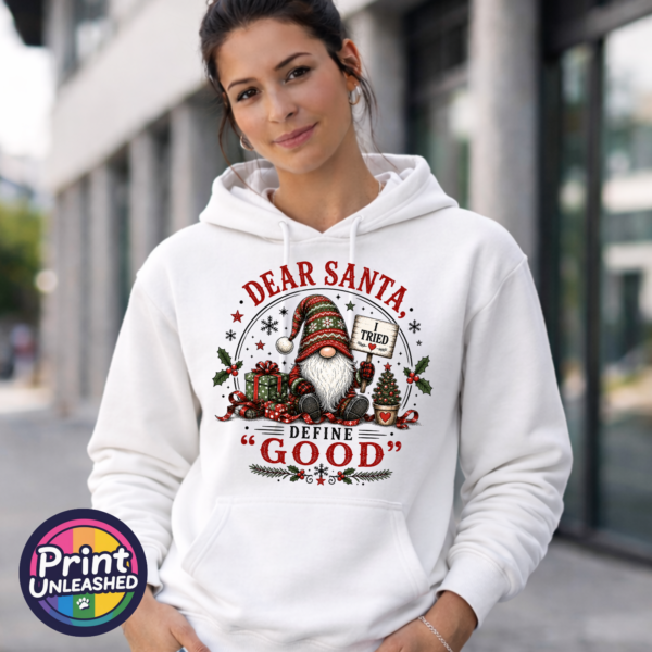 Christmas gonk holding an I Tried sign beside presents and a small tree, with Dear Santa Define Good wording, printed on a white unisex hoodie female model - Print Unleashed