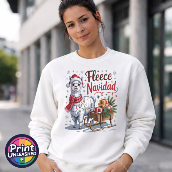 Christmas llama wearing a red knitted hat, tartan scarf and fairy lights beside a gift-filled sleigh, with Fleece Navidad wording on a white unisex sweatshirt female model - Print Unleashed