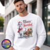 Christmas llama wearing a red knitted hat, tartan scarf and fairy lights beside a gift-filled sleigh, with Fleece Navidad wording on a white unisex sweatshirt male model - Print Unleashed