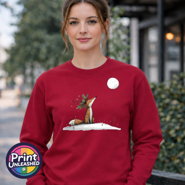 Fox & Moon sweat model female Fox wearing a crown of holly and berries gazing at a full moon from a snowy hill, printed on a cherry red unisex sweatshirt female model - Print Unleashed