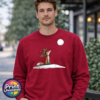 Fox wearing a crown of holly and berries gazing at a full moon from a snowy hill, printed on a cherry red unisex sweatshirt male model - Print Unleashed