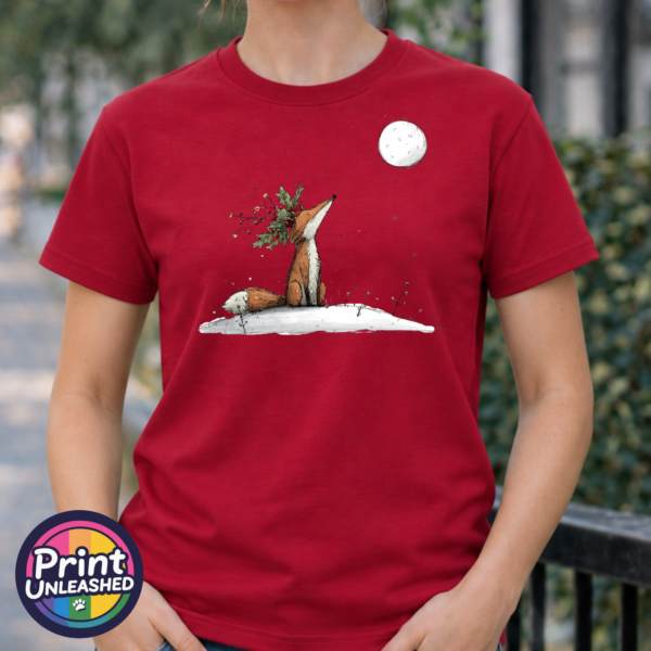 Fox wearing a crown of holly and berries gazing at a full moon from a snowy hill, printed on a cherry red premium unisex T-shirt female model - Print Unleashed