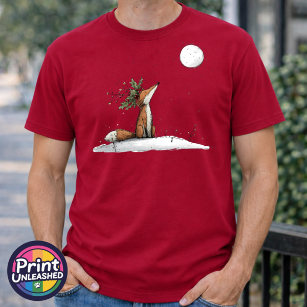 Fox wearing a crown of holly and berries gazing at a full moon from a snowy hill, printed on a cherry red premium unisex T-shirt male model - Print Unleashed