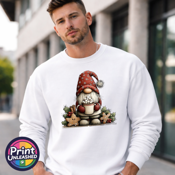 Christmas gonk in a red snowflake-patterned hat holding hot chocolate piled with marshmallows, surrounded by gingerbread stars and holly, printed on a white unisex sweatshirt male model - Print Unleashed