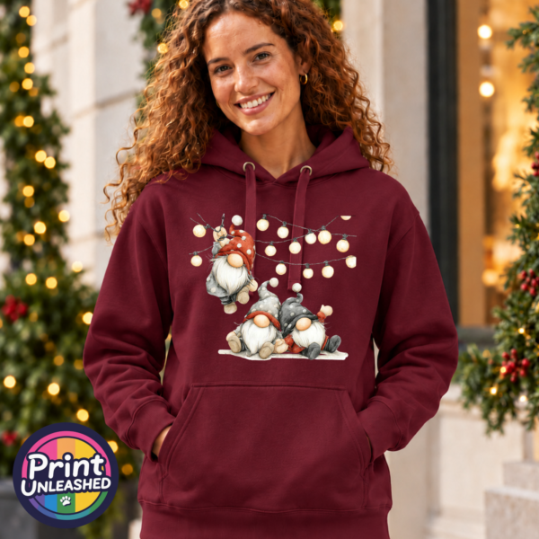 Classic Hoodie featuring three Christmas gonks in red and grey spotted hats, with one hanging from strings of warm glowing lights above two seated companions, model image - Print Unleashed