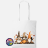 Three autumn gonks in tall pointed hats with pumpkins, a takeaway cup, a black cat and falling leaves printed on a white tote bag - Print Unleashed