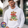 Gingerbread-style signpost pointing to Gingerbread Village, Peppermint Post, Cookie Kitchen and Gumdrop Lane, with sweets and biscuits, printed on a white unisex hoodie male model - Print Unleashed