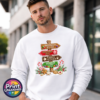 Gingerbread-style signpost pointing to Gingerbread Village, Peppermint Post, Cookie Kitchen and Gumdrop Lane, with sweets and biscuits, printed on a white unisex sweatshirt male model - Print Unleashed