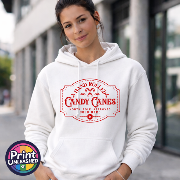 Vintage red Hand Rolled Candy Canes sign with crossed candy canes, holly, North Pole Approved wording and a five-cent emblem, printed on a unisex hoodie female model - Print Unleashed
