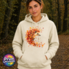 Hedgehog surrounded by swirling orange, red and golden autumn leaves on a softstyle hoodie model - Print Unleashed