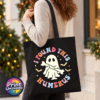 Cute ghost holding a bone beneath colourful I Found This Humerus lettering, surrounded by bats and stars, printed on a tote bag model - Print Unleashed