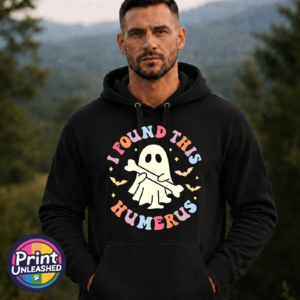 Cute ghost holding a bone beneath colourful I Found This Humerus lettering, surrounded by bats and stars, printed on an Everyday Hoodie model - Print Unleashed