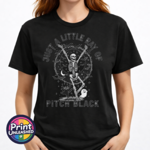 Model image of unisex T-shirt featuring a dancing skeleton with bats, a crescent moon, stars, a cat and ghost beneath Just a Little Ray of Pitch Black lettering - Print Unleashed