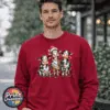 Three Christmas cows tangled in colourful lights, one wearing a Santa hat and another holding a candy cane, printed on a cherry red unisex sweatshirt male model - Print Unleashed