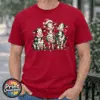 Three Christmas cows tangled in colourful lights, one wearing a Santa hat and another holding a candy cane, printed on a cherry red premium unisex T-shirt male model - Print Unleashed