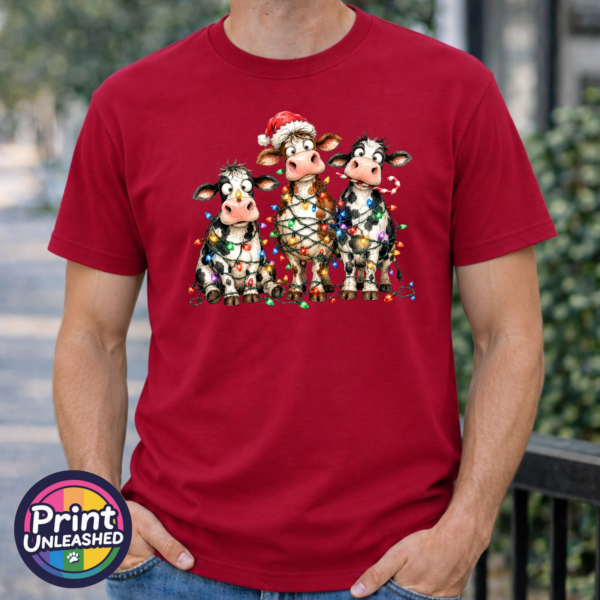 Lights tee model male Three Christmas cows tangled in colourful lights, one wearing a Santa hat and another holding a candy cane, printed on a cherry red premium unisex T-shirt male model - Print Unleashed