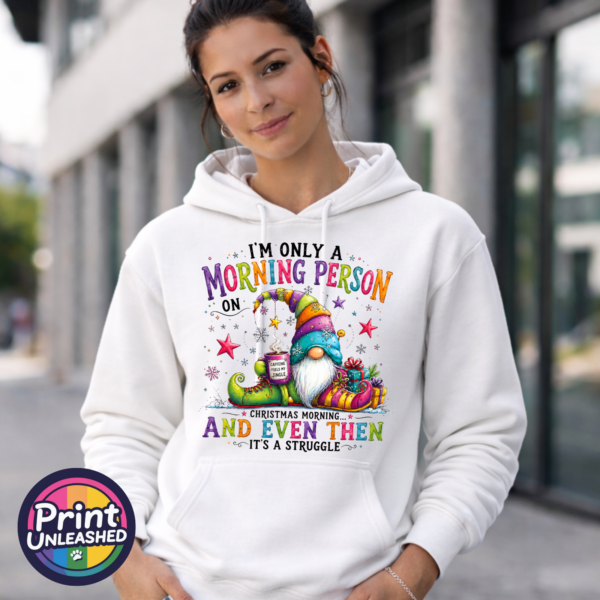 Colourful Christmas gonk holding a steaming coffee mug beside presents, with funny Christmas morning person wording, printed on a unisex hoodie female model - Print Unleashed