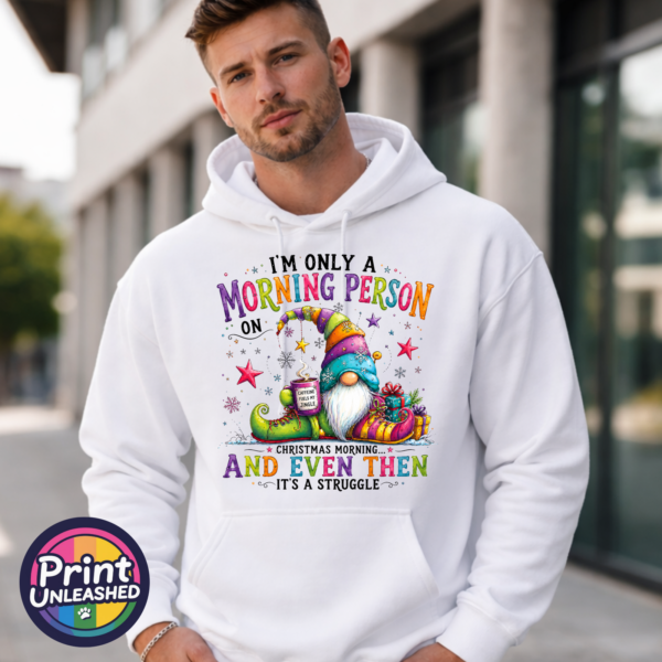 Colourful Christmas gonk holding a steaming coffee mug beside presents, with funny Christmas morning person wording, printed on a unisex hoodie male model - Print Unleashed