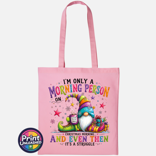 Morning Person Gonk light pink Colourful Christmas gonk holding a steaming coffee mug beside presents, with funny Christmas morning person wording, printed on a light pink tote bag - Print Unleashed