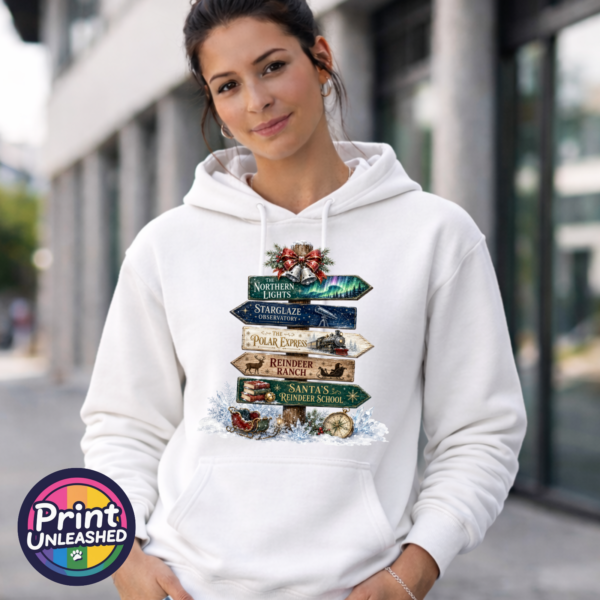 Festive signpost with Northern Lights, observatory and reindeer destinations, decorated with bells, a sleigh and snowy details, printed on a white unisex hoodie female model - Print Unleashed