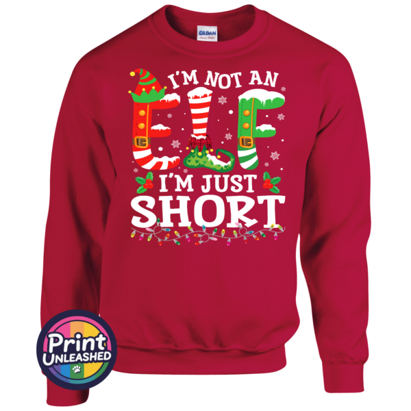 I’m not an elf I’m just short wording with red and green elf-style letters, striped stockings, holly and Christmas lights printed on a cherry red unisex sweatshirt - Print Unleashed