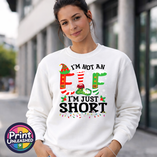 Not An Elf sweat model female Iām not an elf Iām just short wording with red and green elf-style letters, striped stockings, holly and Christmas lights printed on a white unisex sweatshirt model image - Print Unleashed