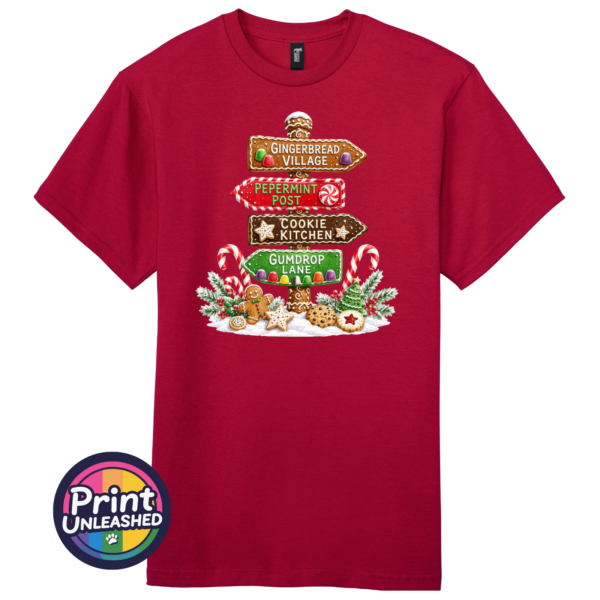 Signpost Gingerbread tee Gingerbread-style signpost pointing to Gingerbread Village, Peppermint Post, Cookie Kitchen and Gumdrop Lane, with sweets and biscuits, printed on a cherry red premium unisex T-shirt - Print Unleashed