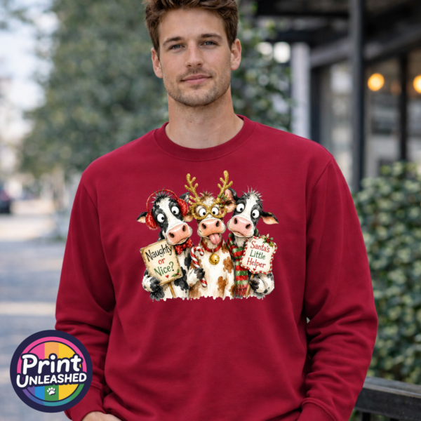 Three Christmas cows with antler glasses, earmuffs and Naughty or Nice and Santa’s Little Helper signs printed on a cherry red unisex sweatshirt male model - Print Unleashed