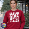 Bold retro-style Sleigh Girl Sleigh lettering with stars and a silhouette of Santa’s sleigh pulled by reindeer, printed on a cherry red unisex sweatshirt model - Print Unleashed