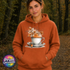 Teacup and saucer with copper and cream autumn leaves, berries and swirling orange steam printed on a softstyle hoodie in texas orange model - Print Unleashed
